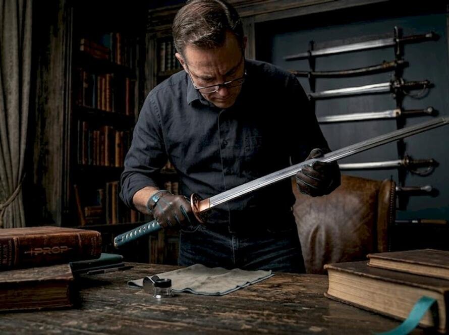 Sword collector inspecting katana in home study