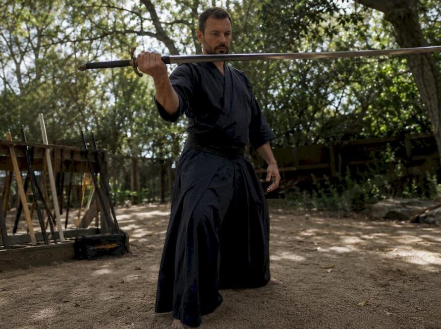 Martial artist testing sword balance in dojo
