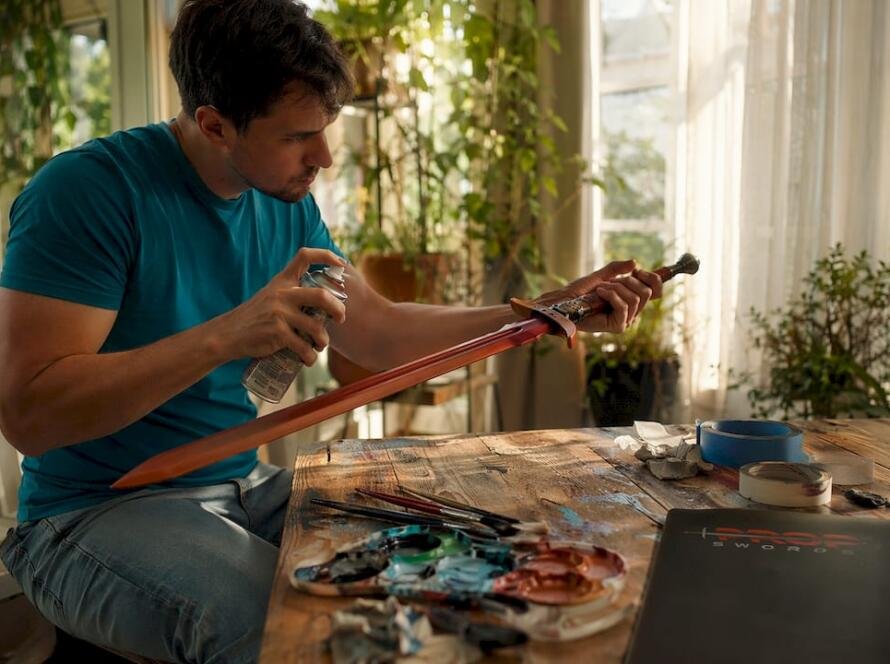 Hobbyist priming prop sword in craft studio